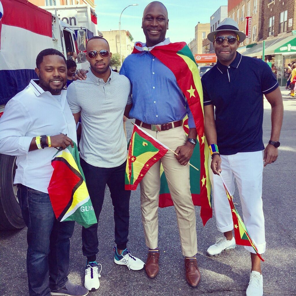 Jonnel Doris and Gregg Bishop, draped in Guyana and Grenada's flags, as they take a photo with friends during NYC's 2019 Labor Day Parade.
