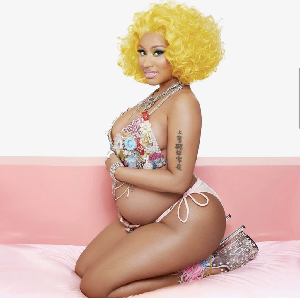 Nicki Minaj accessorizes her pregnanat belly with yellow wig and bejeweled bikini to match - plus sky high platform clear heels!